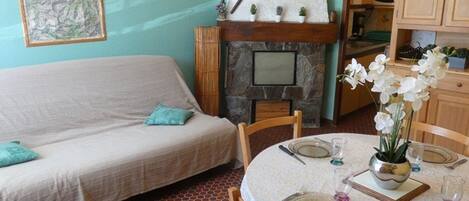 Una habitación con sofá, una mesa de comedor para dos personas, chimenea y un mapa en la pared.