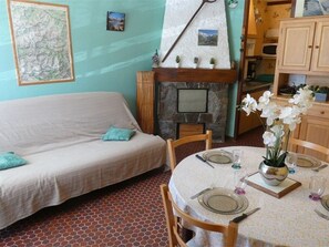 Ein Zimmer mit einer Couch, einem Esstisch für zwei Personen, einem Kamin und einer Karte an der Wand.