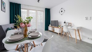 Moderni olohuone, jossa on ruokailutila, televisio ja seinällä oleva kello.