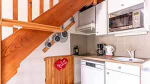A compact kitchen with a wooden staircase, a microwave, a coffee maker, and a dishwasher. - Cozy Maisonette 300m from Beach in Biscarrosse – Sleeps 4, Terrace, Parking (Biscarrosse)