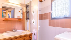 A bathroom with a wooden vanity, a sink, a mirror, a shower with a frosted glass door, and a toilet. - Cozy Maisonette 300m from Beach in Biscarrosse – Sleeps 4, Terrace, Parking (Biscarrosse)