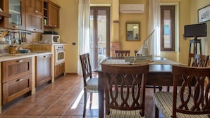 A cozy kitchen with wooden cabinets, a dining table with chairs, and a sailboat model. - Foscolo 8 in Alghero (Alghero)