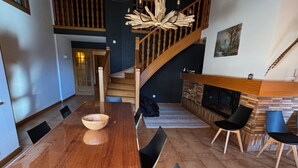 A modern dining area with a wooden table, black chairs, a staircase, and a fireplace. - Spacious duplex for 20 near slopes in La Chapelle-d'Abondance (La Chapelle-d'Abondance)
