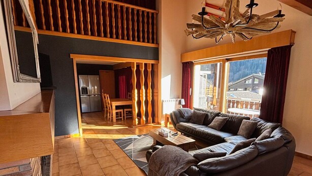 A spacious living room with a large leather sofa, a wooden dining table, and a kitchen in the background. - Spacious duplex for 20 near slopes in La Chapelle-d'Abondance (La Chapelle-d'Abondance)