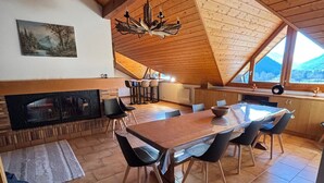 A spacious dining area with a wooden table and chairs, a fireplace, and a view of the mountains through large windows. - Spacious duplex for 20 near slopes in La Chapelle-d'Abondance (La Chapelle-d'Abondance)