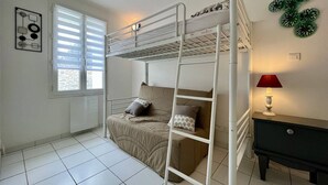 Habitación con literas, una ventana, una lámpara y un aparador.