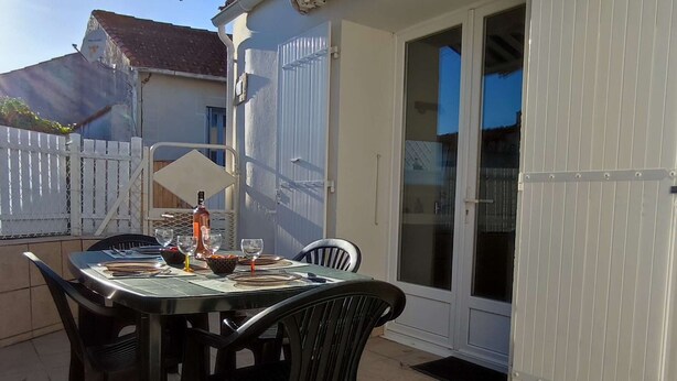 Un patio al aire libre con una mesa lista para comer, rodeado de sillas.