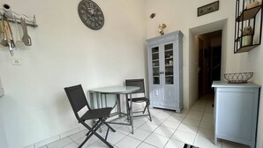 Un comedor con una mesa redonda y dos sillas, un armario con puertas de cristal y un reloj de pared.