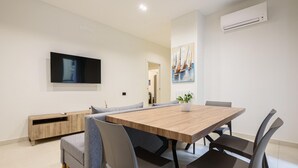 Een moderne eethoek met een houten tafel, een grijze gestoffeerde bank en zwarte stoelen.