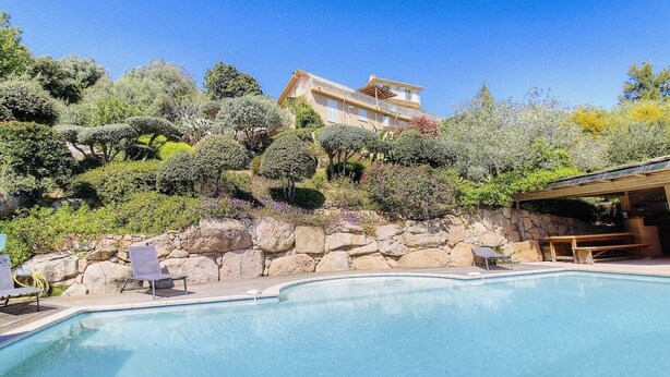 A swimming pool with lounge chairs and a stone wall. - Atypical house with sea view (Porto-Vecchio)