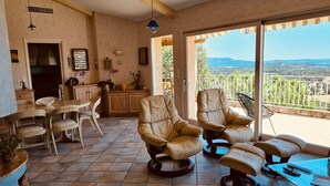 A spacious living area with a dining table, two leather armchairs, a coffee table, and a view of the outdoors. - Atypical house with sea view (Porto-Vecchio)