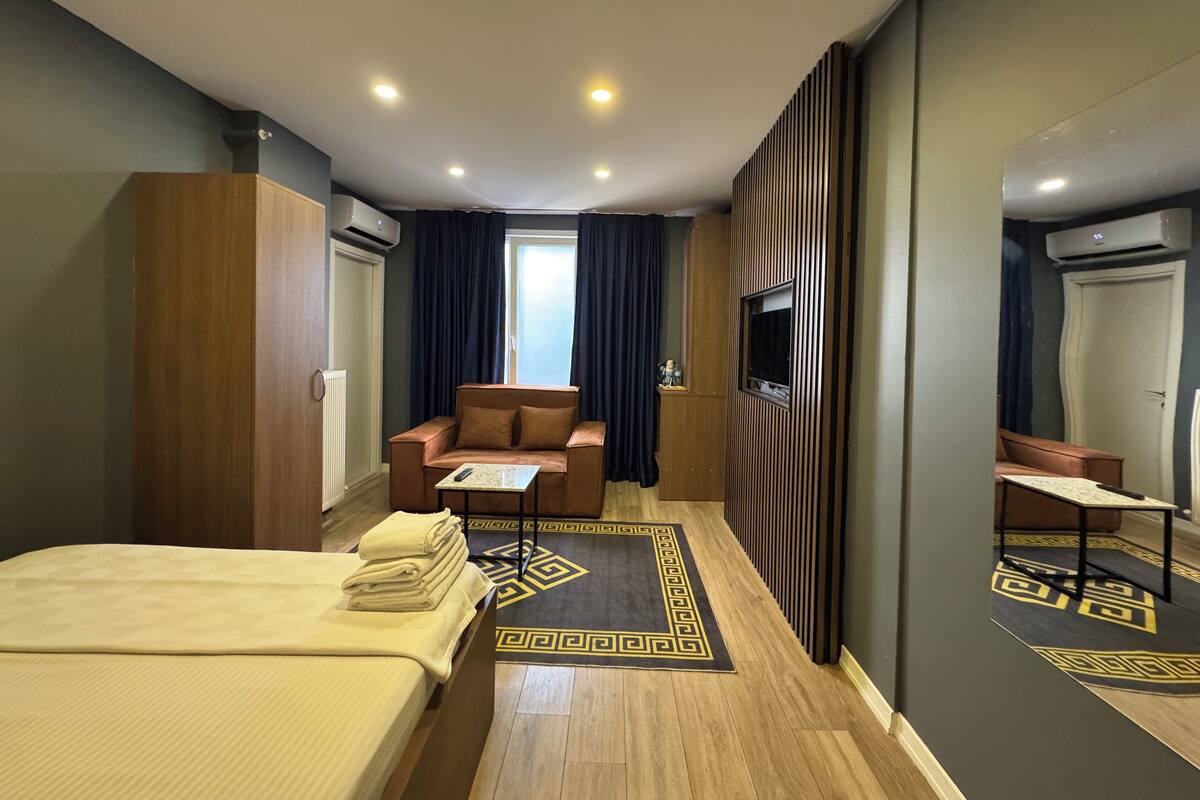 Una habitación de hotel con una cama, un sofá, un televisor y un espejo.