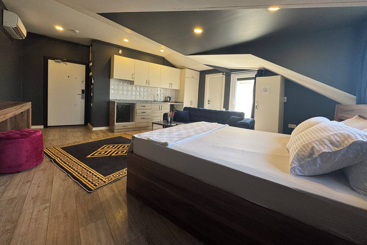 Una habitación compacta con cama, kitchenette y baño.