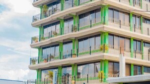 A multi-story building with balconies, a green facade, and a ground-level entrance. - Alexander Hotel & Tours (Iringa)