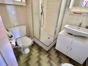 A bathroom with a toilet, shower, sink, and cabinets.
