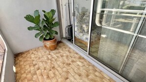 Une pièce avec un sol carrelé, une plante en pot et une porte-fenêtre coulissante.