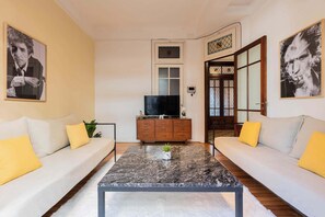 Un salon avec deux canapés, une table basse, un téléviseur et un meuble.