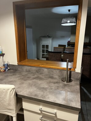A kitchen with a grey countertop, a wooden table, wicker chairs, and a hanging light fixture. - A Little Paradise in Aveyron (Saint-Jean-du-Bruel)
