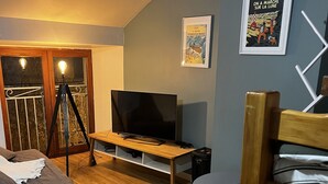 A cozy living room with a TV, a wooden bench, a cat tree, and a bed. - Little paradise in Aveyron (Saint-Jean-du-Bruel)