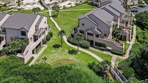 A coastal residential area with modern houses, a beach, and a boardwalk. - Pet Friendly | Ground Floor Sailmaker Villa | Covered Patio with Pool View (Fernandina Beach)