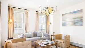A living room with a sofa, armchairs, a coffee table, and a painting on the wall.