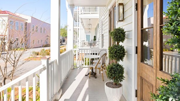 A covered porch with a white railing, a wooden door, and a small table with chairs.