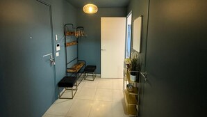 Un pasillo estrecho con un banco, un perchero y una repisa con objetos decorativos.