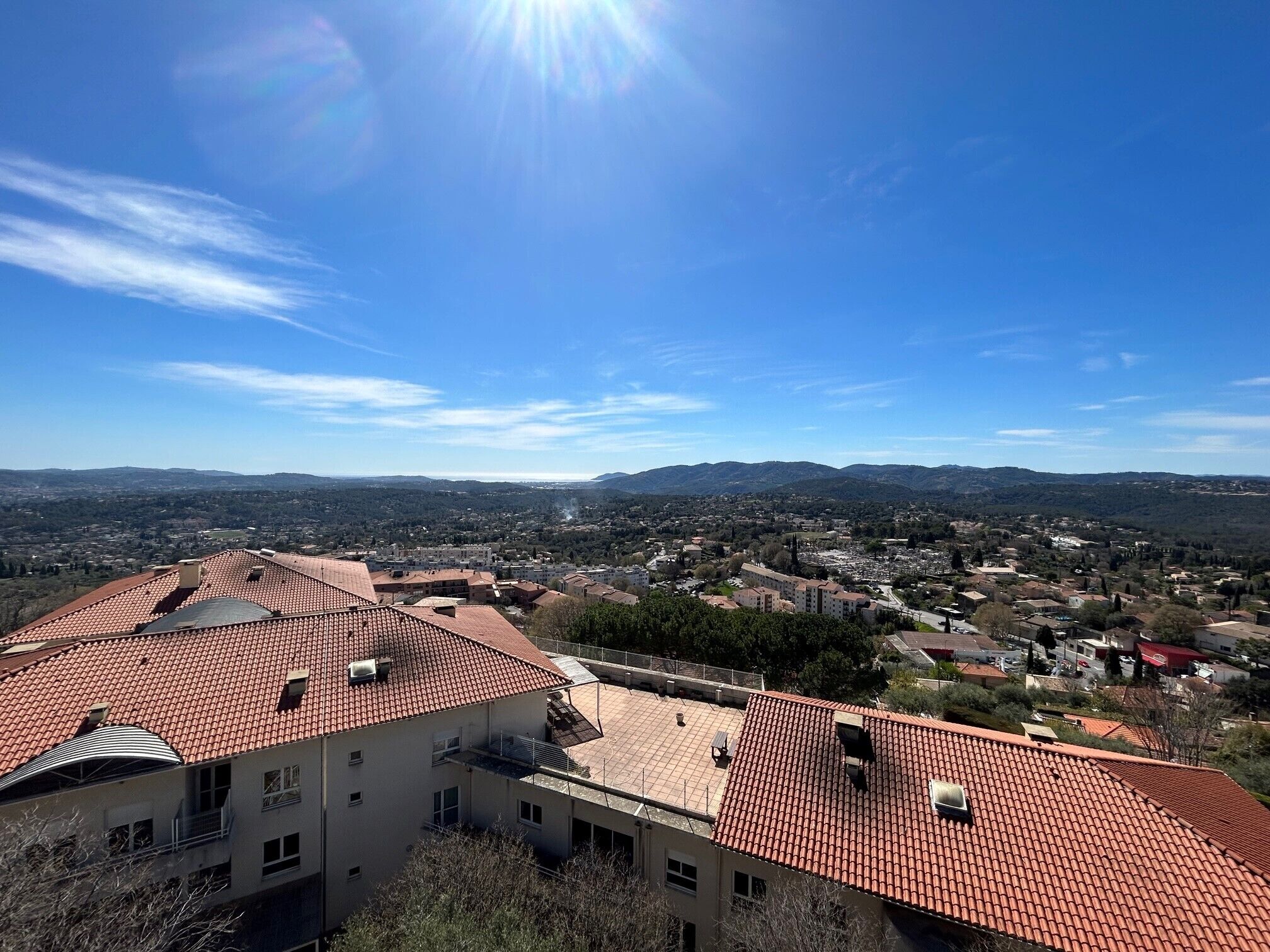 A residential area with red-tiled roofs and a clear blue sky.