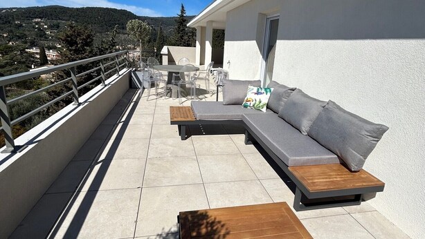 Una terraza en la azotea con un sofá, una mesa de madera y un comedor.