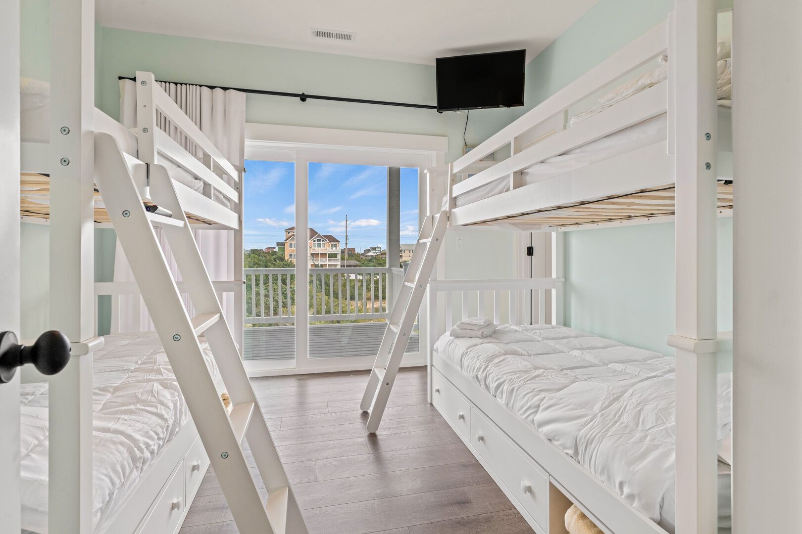 A room with bunk beds, a balcony with a view, and a television.