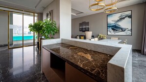 A modern hotel lobby with a marble reception desk, a large plant, and artwork on the walls.
