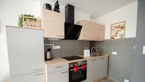 Uma cozinha compacta com forno embutido, cafeteira e chaleira.