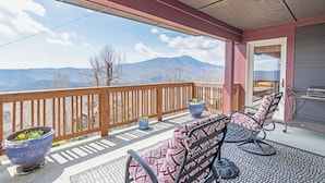 Een balkon met uitzicht op bergen, een barbecue en zitplaatsen buiten.