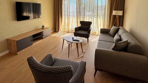 Un salon moderne comprenant un téléviseur à écran plat, un canapé, deux fauteuils, une table basse et un meuble pour la télévision.