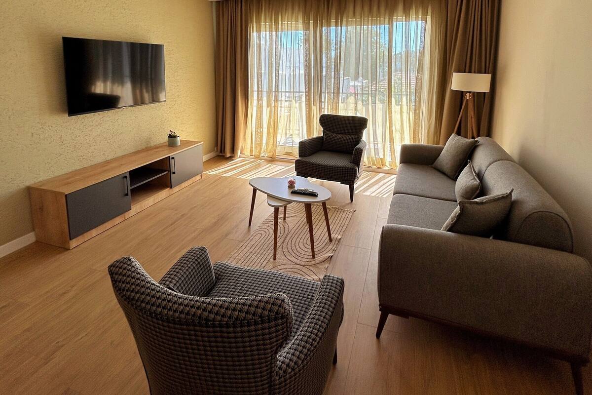 Un salon moderne comprenant un téléviseur à écran plat, un canapé, deux fauteuils, une table basse et un meuble pour la télévision.