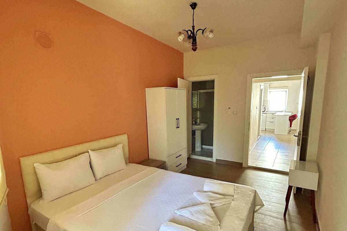 Une chambre à coucher avec un grand lit, une armoire et une salle de bain visible à travers une porte ouverte.