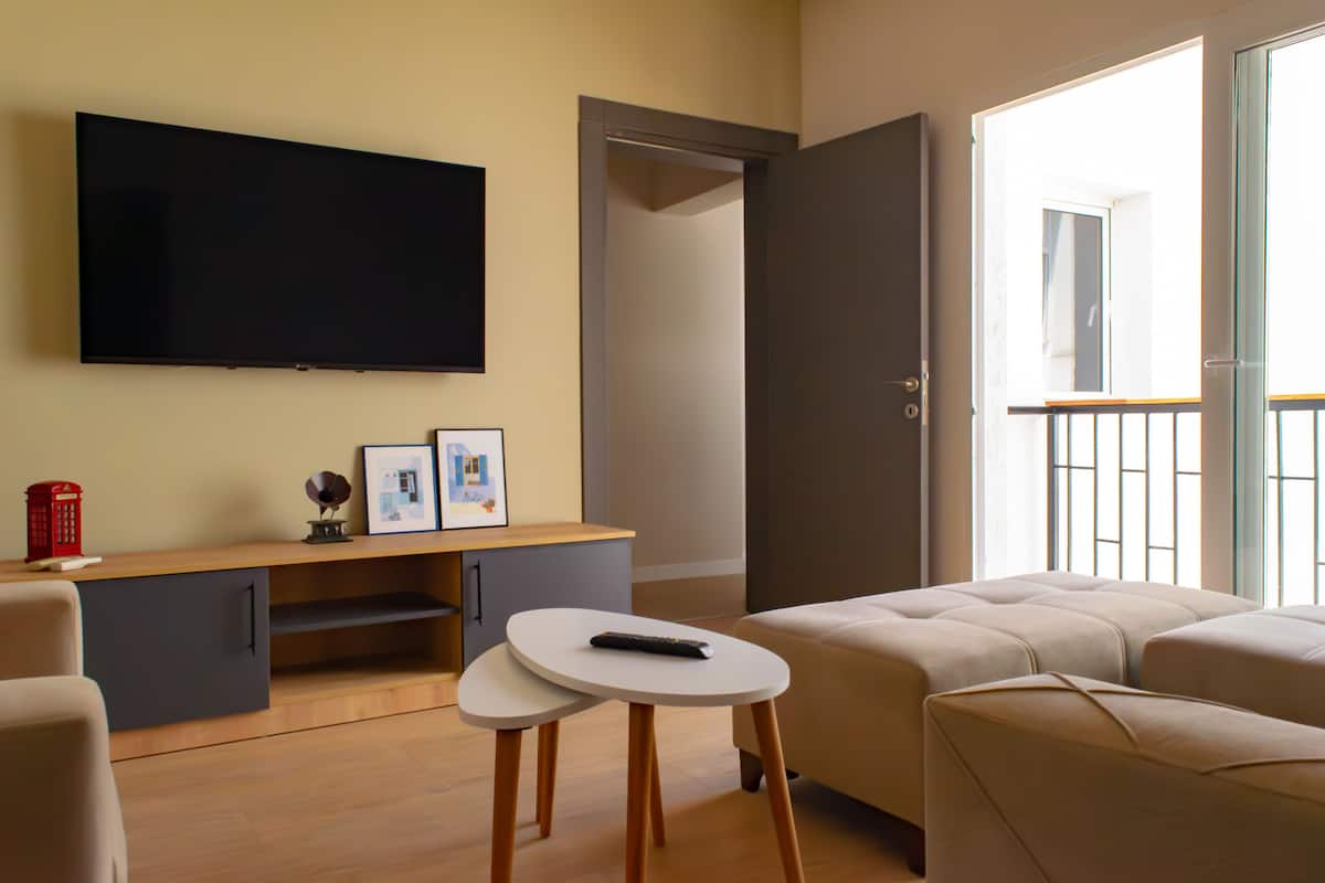 Un salon moderne avec un téléviseur à écran plat, une petite table avec une télécommande et un canapé.
