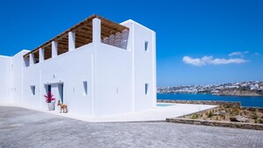A white building with a wooden roof, a pool, and a view of the sea. - Mykonos Town Villa (Mykonos)