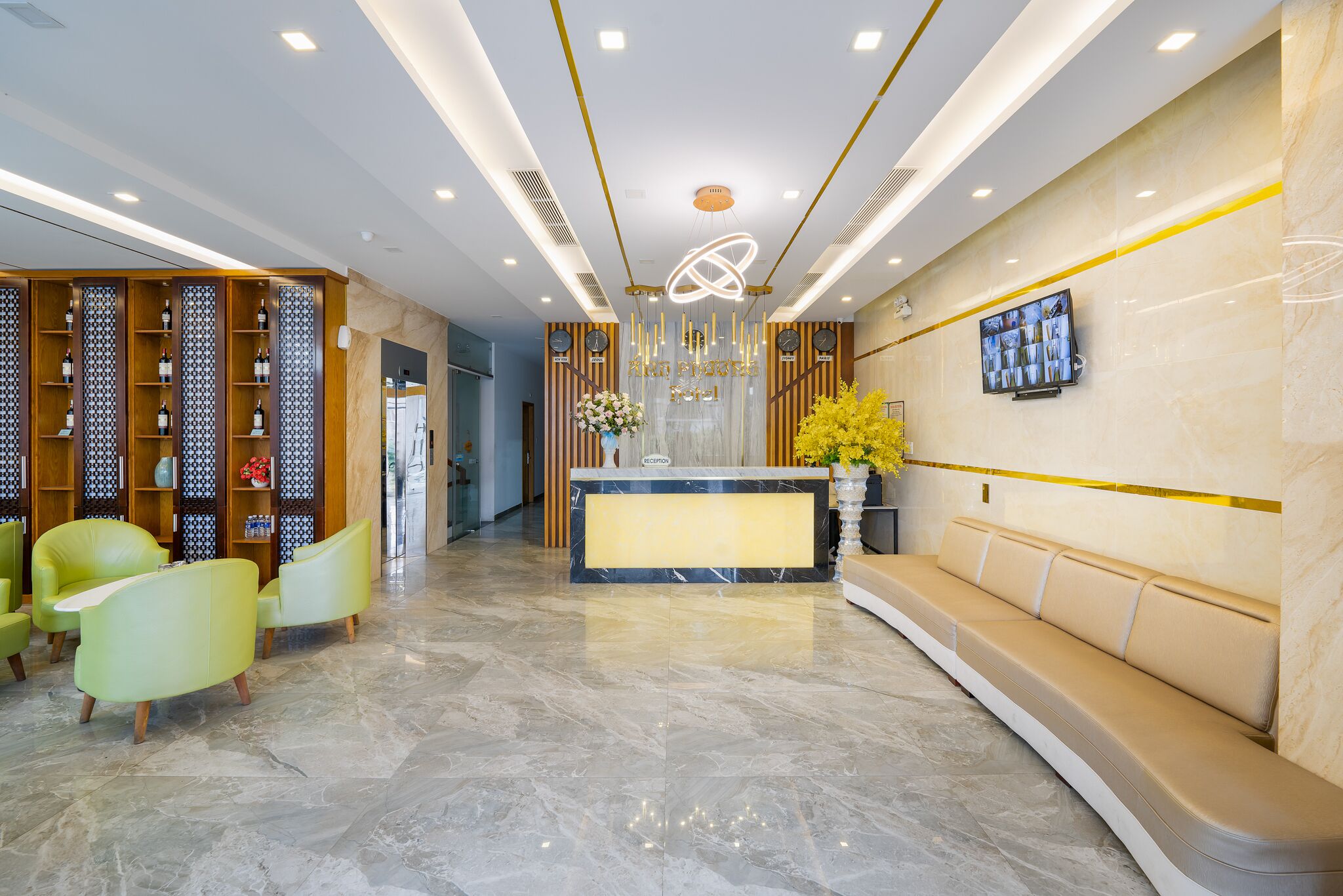 A modern reception area with a marble floor, a reception desk, a seating area, and a wall-mounted TV.