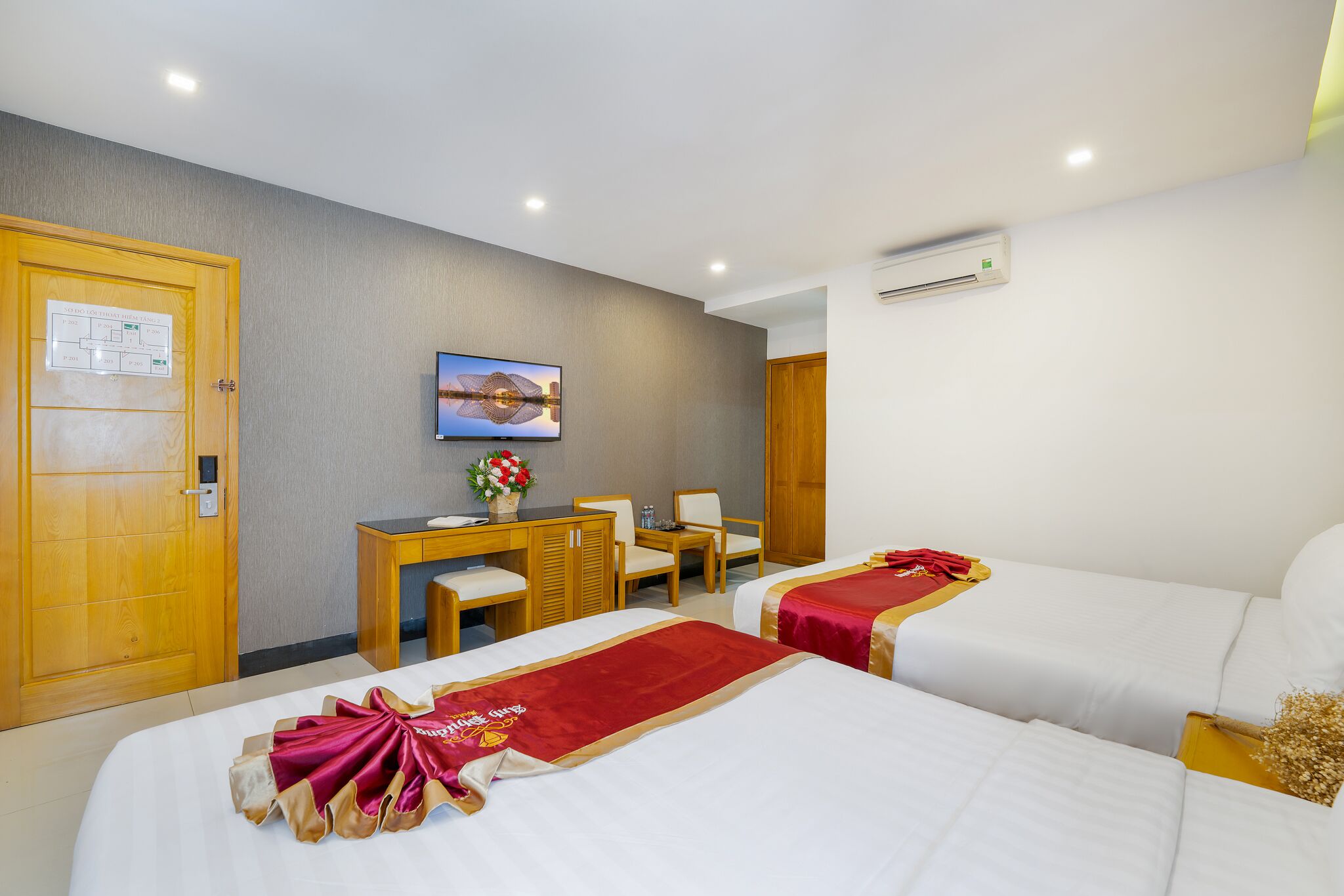 Habitación de hotel con dos camas, un escritorio, una silla, un televisor y un equipo de aire acondicionado.