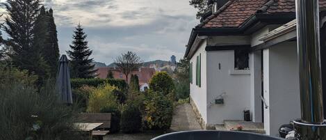 Zona residenziale con vasca idromassaggio, panche di legno e un edificio bianco con persiane verdi.