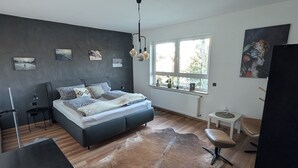 Un dormitorio moderno con una cama grande, un escritorio, una silla y una ventana.
