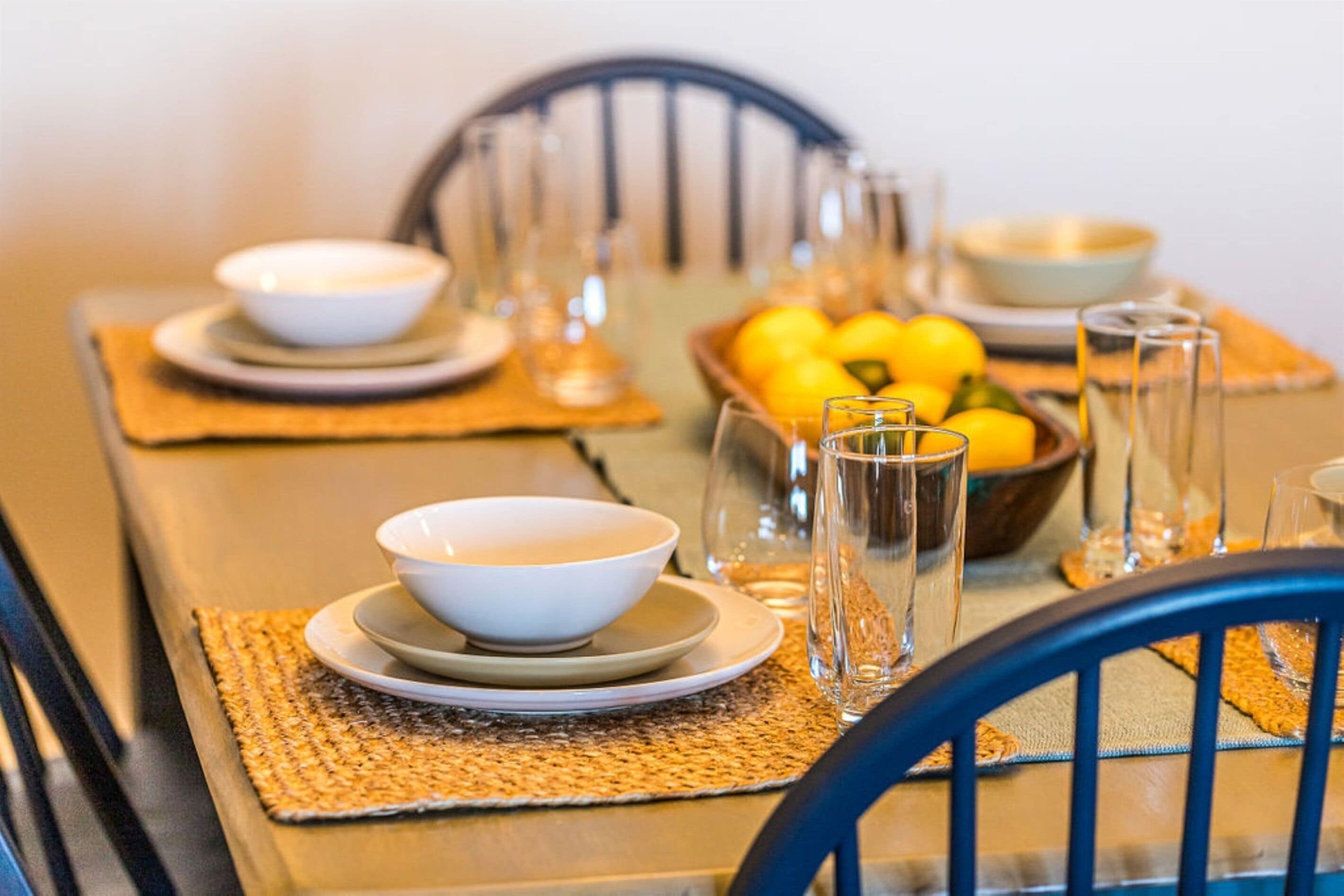 A dining table set with bowls, glasses, and a bowl of lemons.