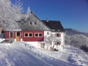 A two-story house with a red and white facade, a sloped roof, and a small porch. - Little Finland (Orbey)