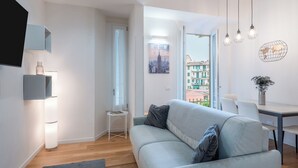 En moderne stue med en lyseblå sofa, et lille sofabord og et spiseområde med et hvidt bord og stole.