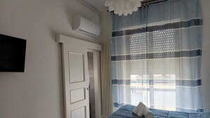 A bedroom with a bed, a door, an air conditioning unit, and a window with curtains. - La Rosa dei Venti (Ortona)