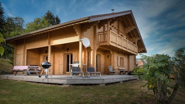 Eine Holzhütte mit Veranda, Sitzgelegenheit im Freien und einer Satellitenschüssel.