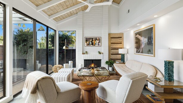 A modern living room with a fireplace, comfortable seating, and large windows.