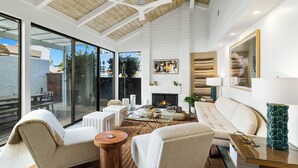 A modern living room with a fireplace, comfortable seating, and a glass door leading to an outdoor area.