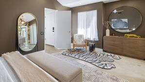 A bedroom with a large mirror, a fluffy chair, a dresser, and a zebra-patterned rug.